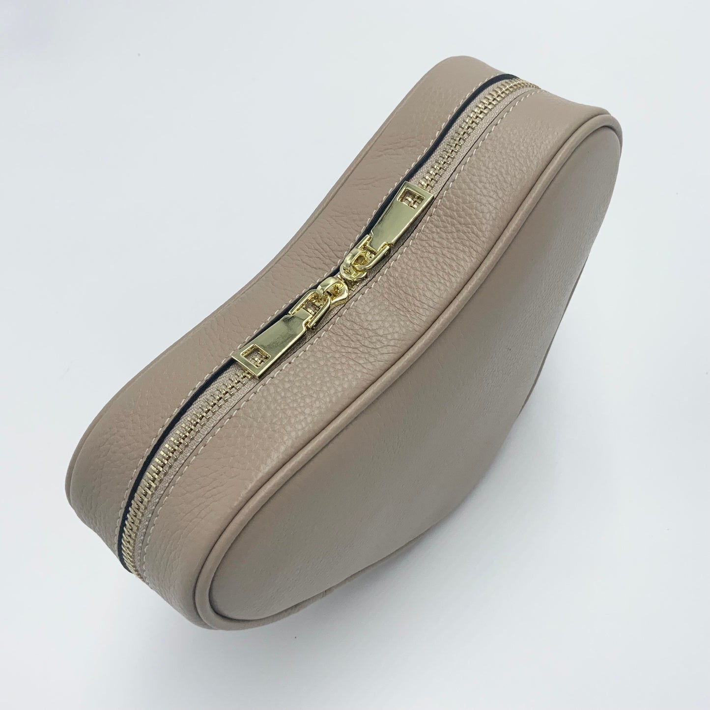 Sand heart-shaped leather crossbody bag by Tikori London, featuring a stylish and compact design perfect for everyday use. Pictured from the top showing the zipper detail.