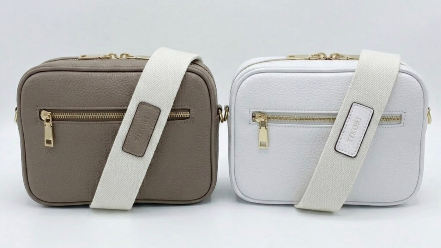 TIKORI classic Mink and White by TIKORI London. Classic elegance with practicality and versatility in mind. Taupe and white leather cross body bag shows in the picture with golden tone hardware and TIKORI canvas strap. Front profile includes the gold zipper pocket. Bag display in a white background.