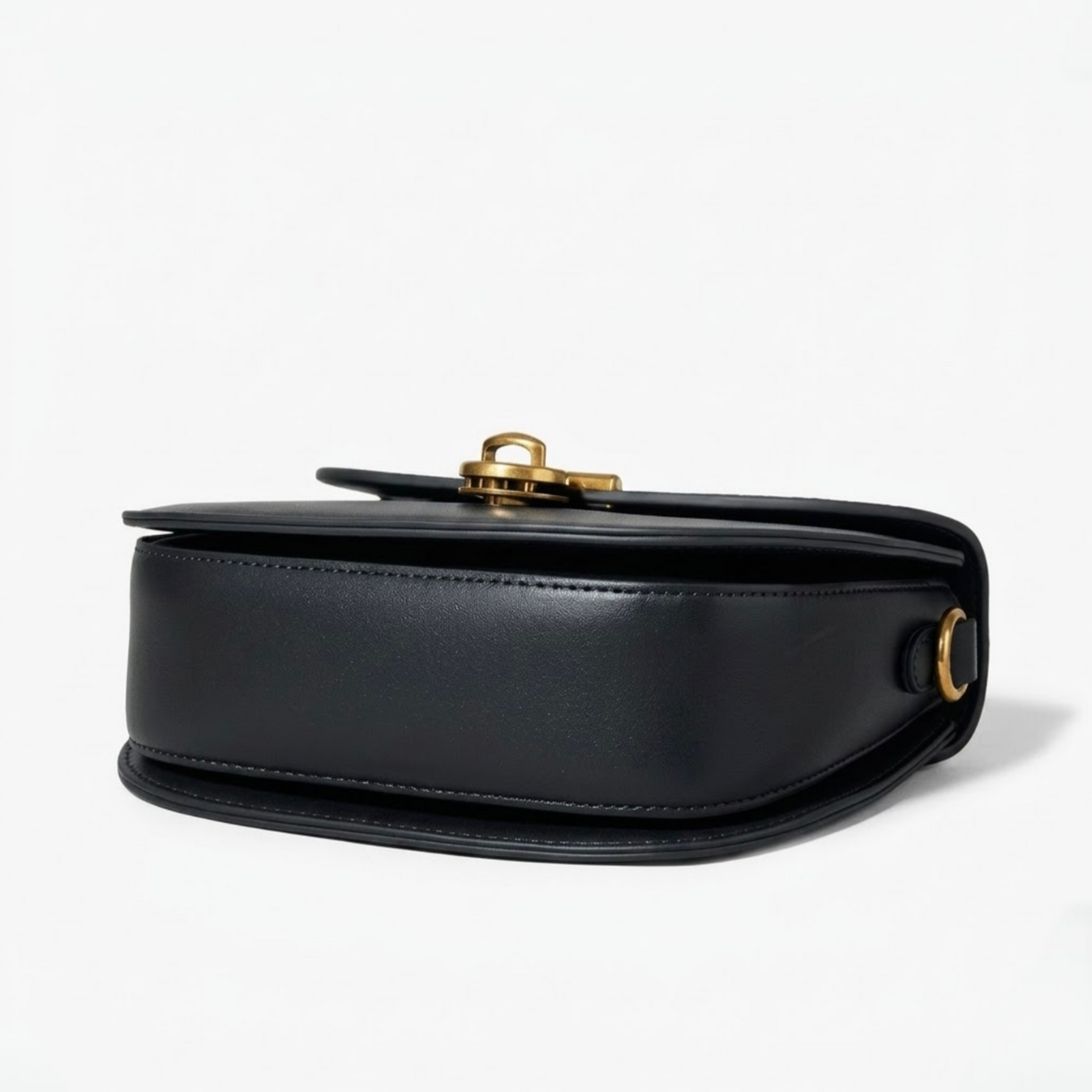 Luna saddle bag - Black - TIKORI LONDON. Black bag is laying facing up, and bottom of the profile of the bag showing in the picture. 