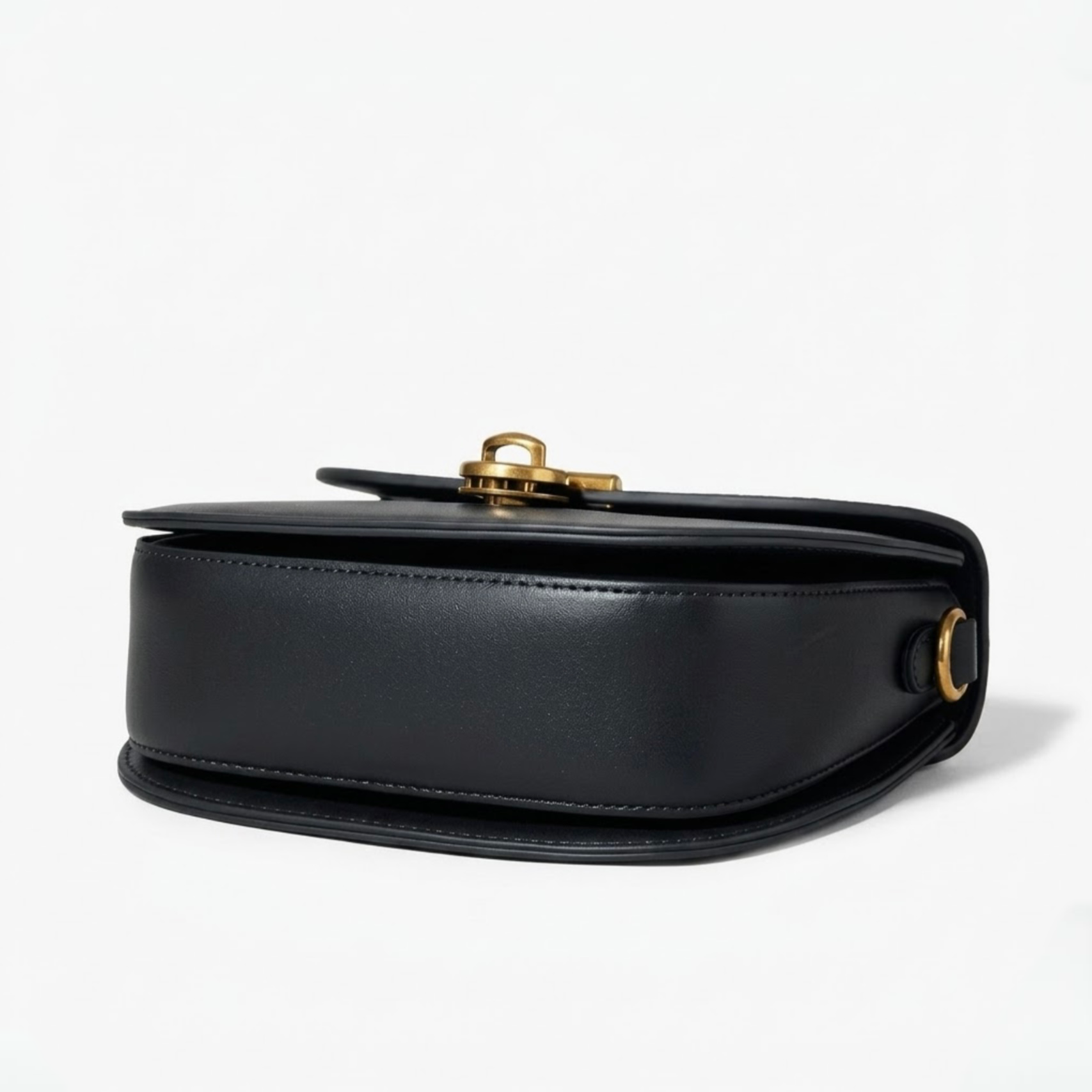 Luna saddle bag - Black - TIKORI LONDON. Black bag is laying facing up, and bottom of the profile of the bag showing in the picture. 
