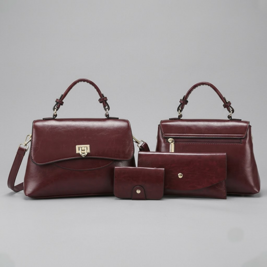Heritage flap bag maroon by TIKORI LONDON. Defined by a unique braided leather handle that adds a touch of luxury. Features a beautiful, sweeping front flap secured by a polished, shield shaped gold clasp. One bag facing front and the other facing back showing both profiles. Card holder and wallet also sit next to bags. Display on the floor.