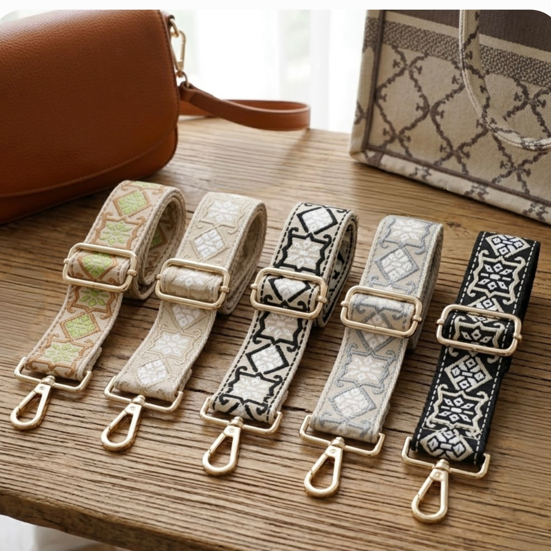 Woven geometric patterned Cross Body Bag Straps By TIKORI london. Soft geometric patterns with sleek design with golden tone hardware. For instance style upgrade. 5 straps displays on a wooden table next to two beautiful handbags, home background.