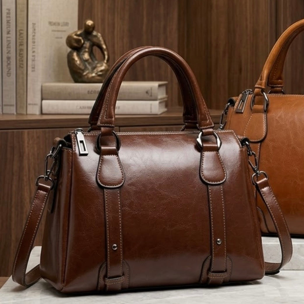 Vintage Brown Polished Satchel Bag by TIKORI LONDON. Crafted from high quality genuine leather, this bag offers a luxurious aesthetic with a durable finish that stands up to daily wear. Both light brown and dark brown bags are displays in the picture in a modern boutique environment. Some books on dark brown bag shows more in the picture. 