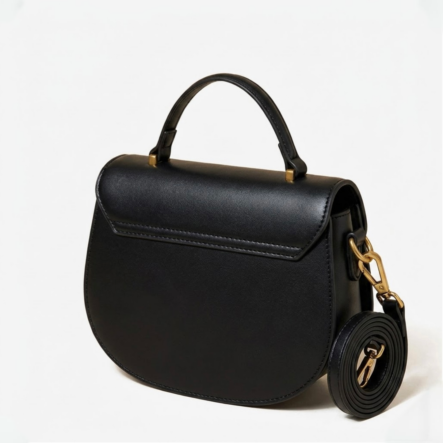 Luna saddle bag - Black - TIKORI LONDON. Black bags back profile is showing in the picture. Golden hardware and strap next to the bag and top handle showing in a fully white background. 