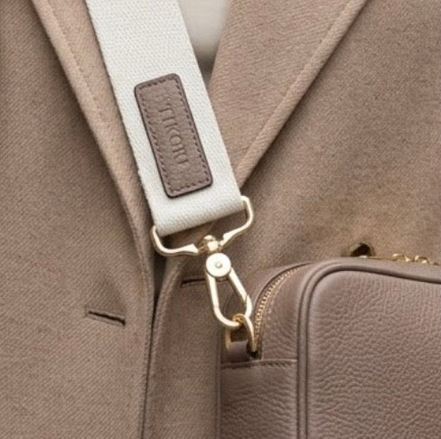 TIKORI classic mink by TIKORI London. Classic elegance with practicality and versatility in mind.  Close up detail of the bags canvas strap shows in the picture  Model wear beige coat and wears mink cross body. 