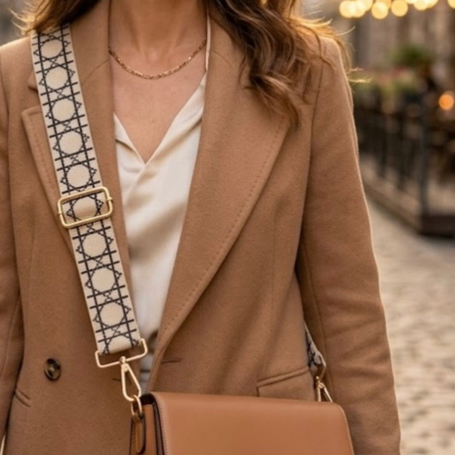 Ivory checkerboard lines crossbody strap by TIKORI  London with adjustable length and golden metal hardware details. Body of a model in ivory top and tan coat wears bag with ivory strap. Close details of the golden hardware shows in the picture. Street background.