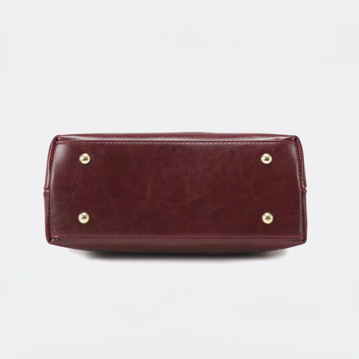 Heritage Flap Bag - Maroon By TIKORI London. Featuring bottom of the handbag showing in the picture with gold legs.