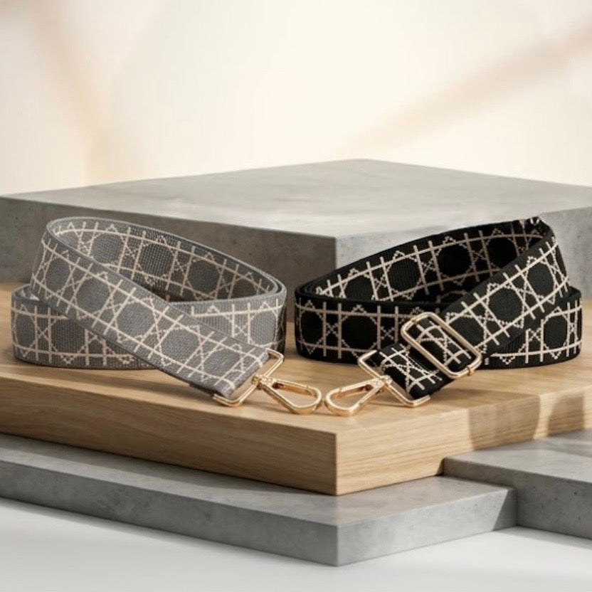 TIKORI London Checkered Lines Crossbody Straps with adjustable length laid and stylish pattern displayed. Black and grey straps laid on a wooden display next to stone block display. Golden hardware also showing in the picture in a cream contemporary background.