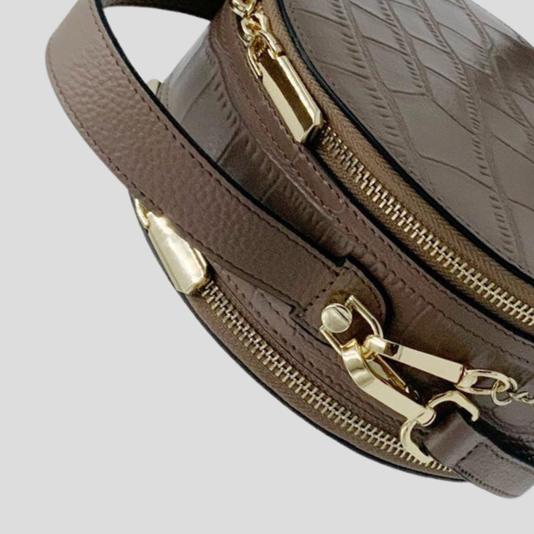 Cleopatra by TIKORI London. Mink leather circle crossbody bag with dual zip fastenings and finished leather design. Close up details of the handle and zipper showing in the picture. 