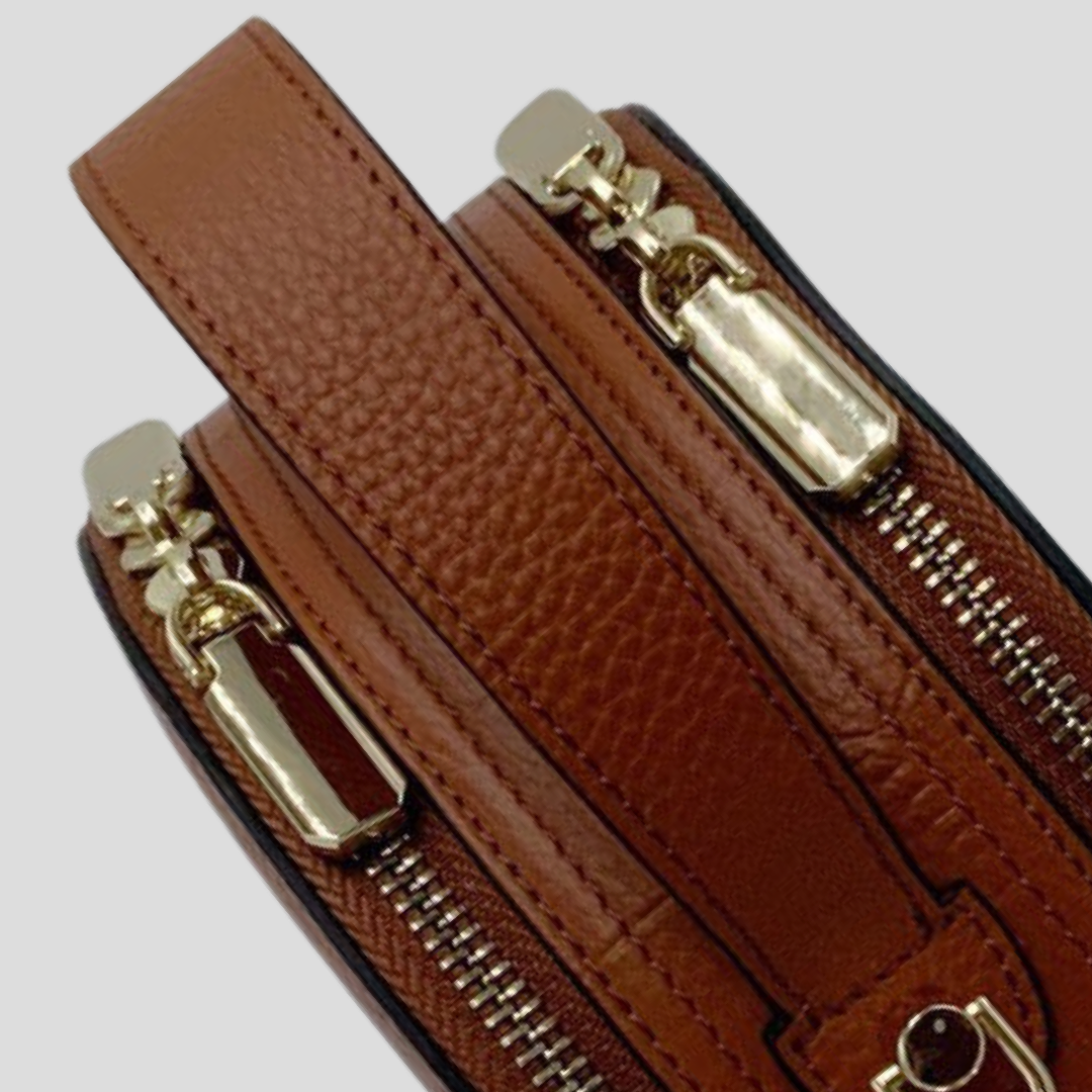 Cleopatra by TIKORI London. warm tan leather circle crossbody bag with dual zip fastening and finished leather design. Close up Top handle shows on the picture.