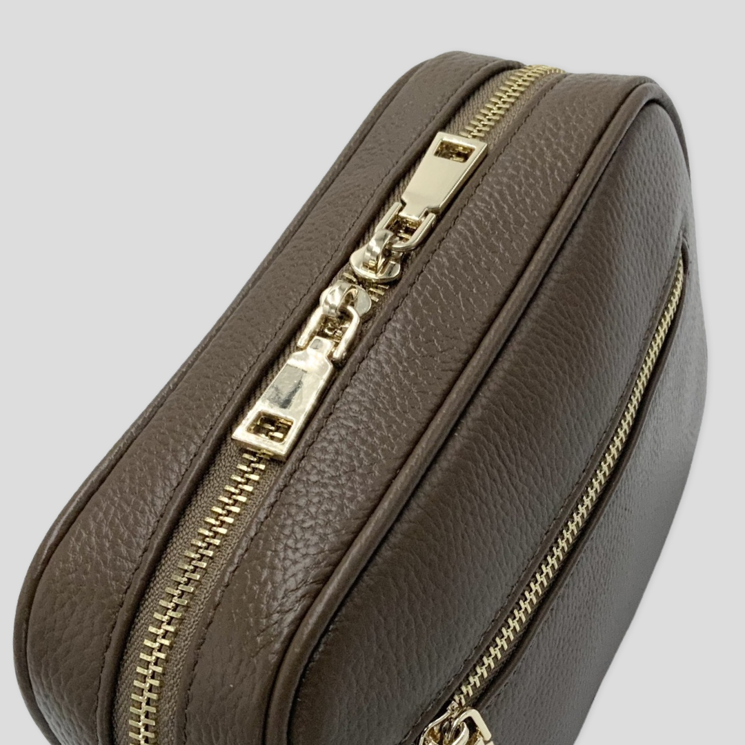 TIKORI  classic dark brown by TIKORI LONDON. Genuine leather crossbody bag. Close up Front profile of the bag showing in the picture. Golden tone hardware and front pocket zipper detail shows in a fully white background 