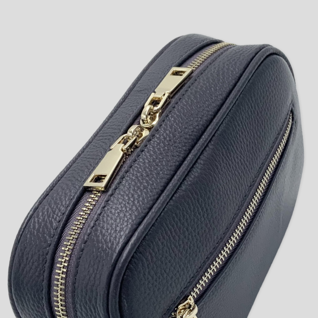 Classic elegance with practicality and versatility in mind. TIKORI classic grey purple by TIKORI London. Crossbody bag Crafted in soft pebbled premium genuine leather. Side profile of the bag showing golden hardware and front pocket with zipper details in white background  