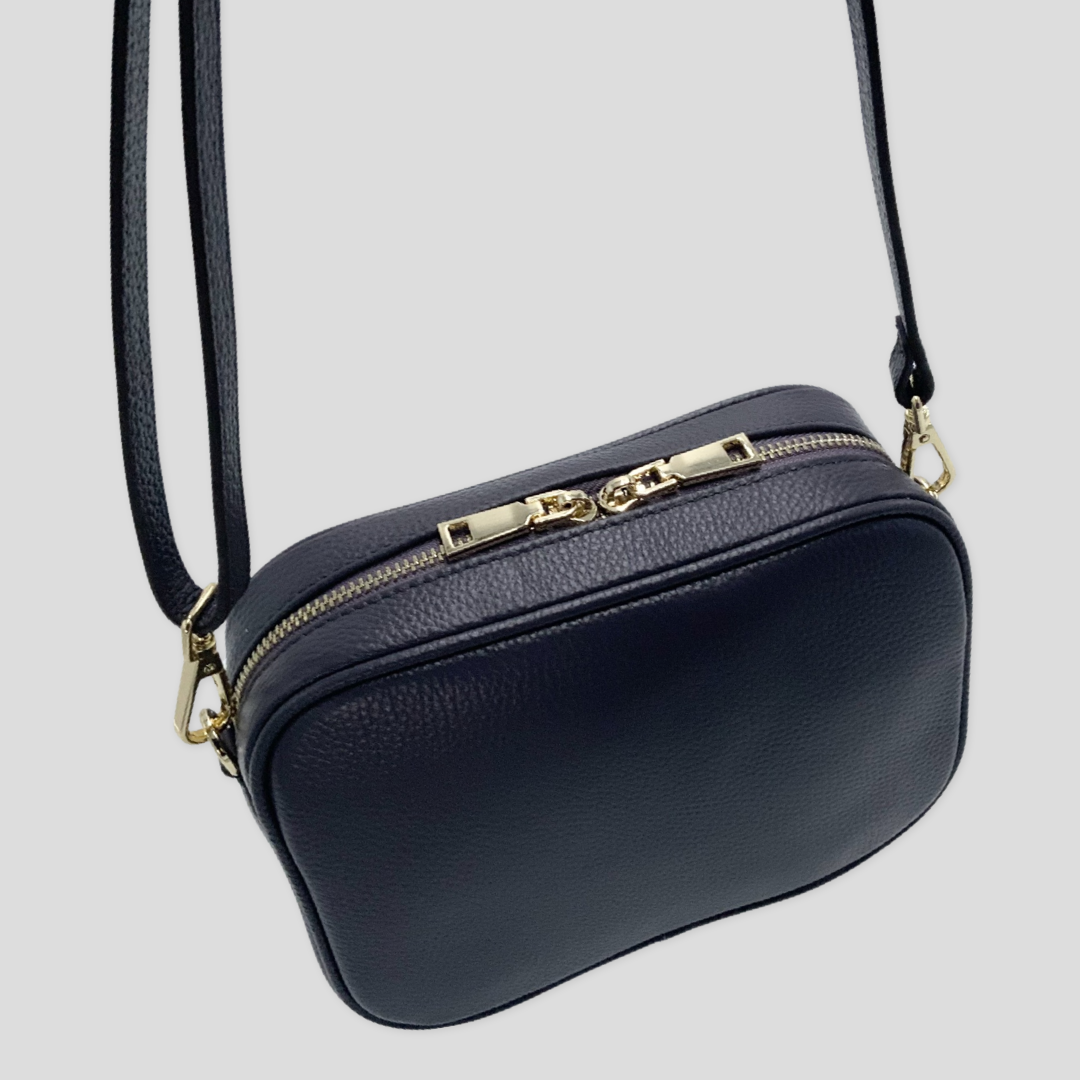 Classic elegance with practicality and versatility in mind. TIKORI classic grey purple by TIKORI London. Crossbody bag Crafted in soft pebbled premium genuine leather. Back profile of the bag showing golden hardware, in hanging motion, with long strap showing in white background 