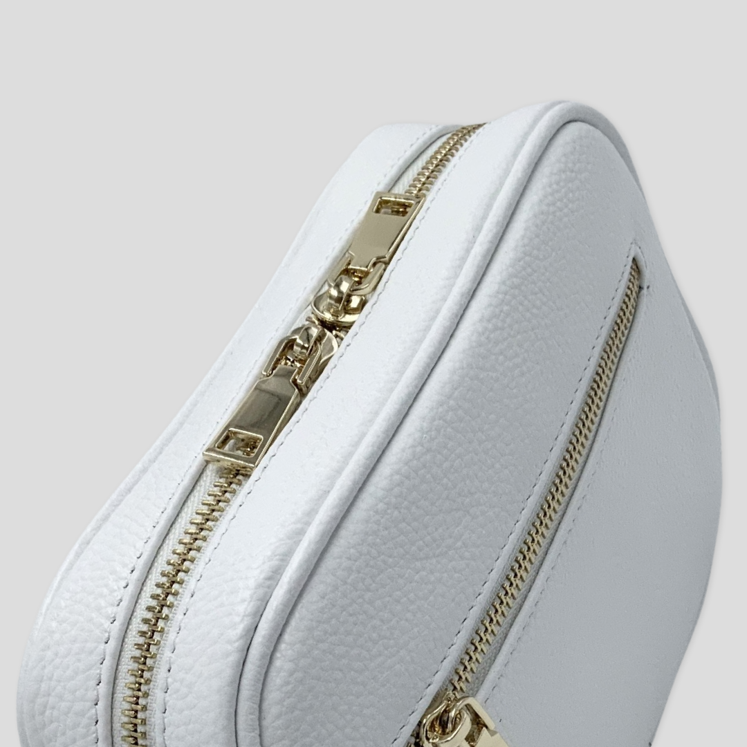 Classic elegance. Tikori Classic White by TIKORI london.  Genuine pebbled leather cross body bag. Picture taken from the top showing front profile. Golden zipper and front pocket with gold hardware in white background shows in the picture.