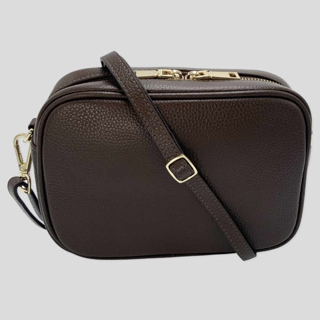 Classic elegance with practicality and versatility in mind. TIKORI classic dark brown by TIKORI london. Genuine leather crossbody bag. Front profile of the bag showing in the picture, leather strap across the bag.  Golden tone hardware and strap gold buckle shows in white background. 