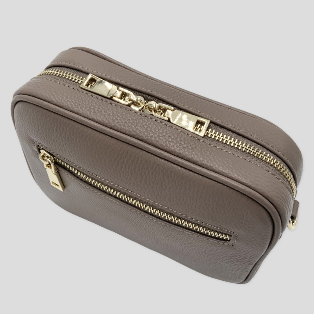 TIKORI classic mink by TIKORI London. Classic elegance with practicality and versatility in mind. Mink leather cross body bag shows in the picture with golden tone hardware. Front profile includes the gold zipper pocket. Bag display in a white background.  