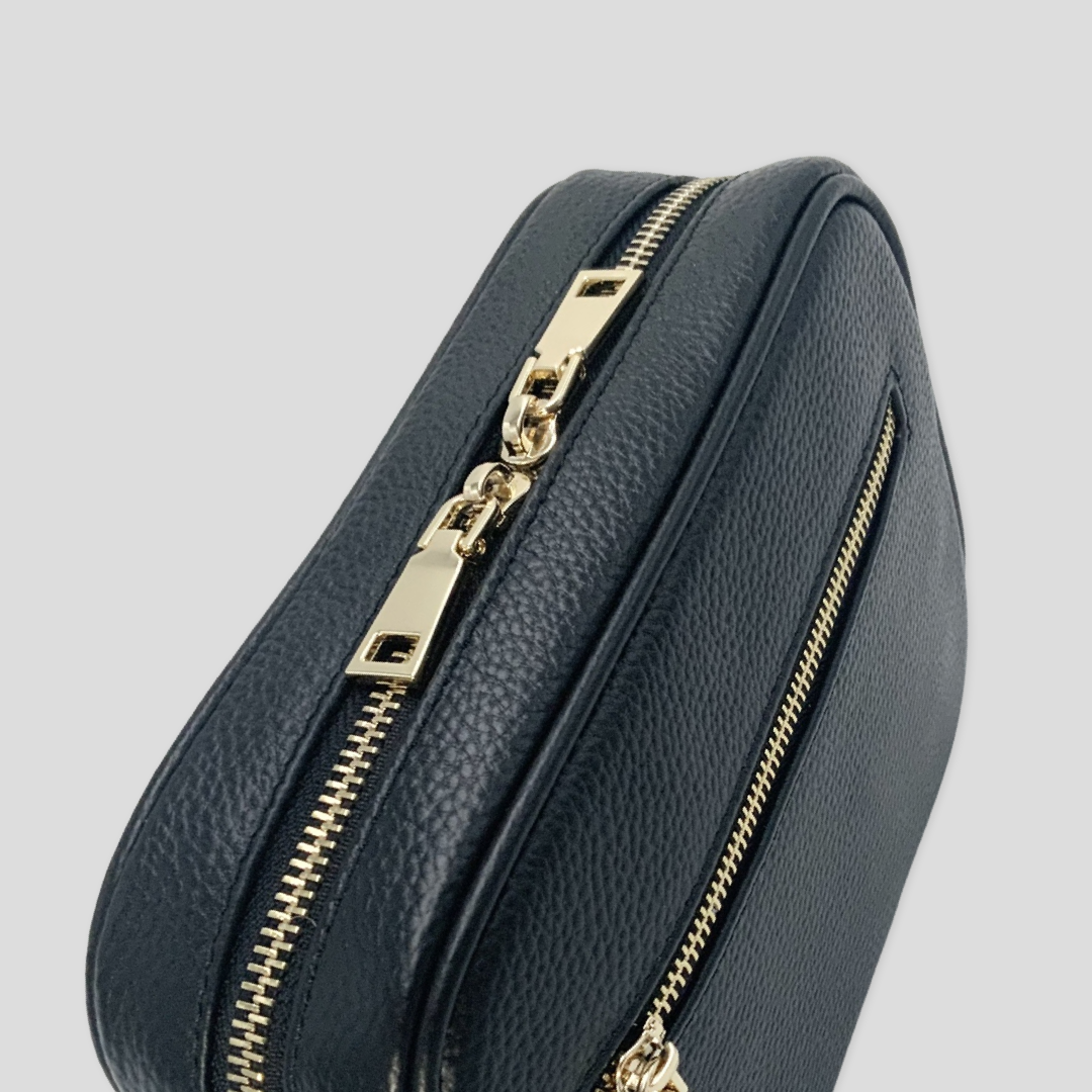 Classic elegance with practicality and versatility in mind. TIKORI classic Black by TIKORI london. Top angled picture of the bag shows with golden tone hardware in the white background. Bag front pocket with golden hardware is also prominent.