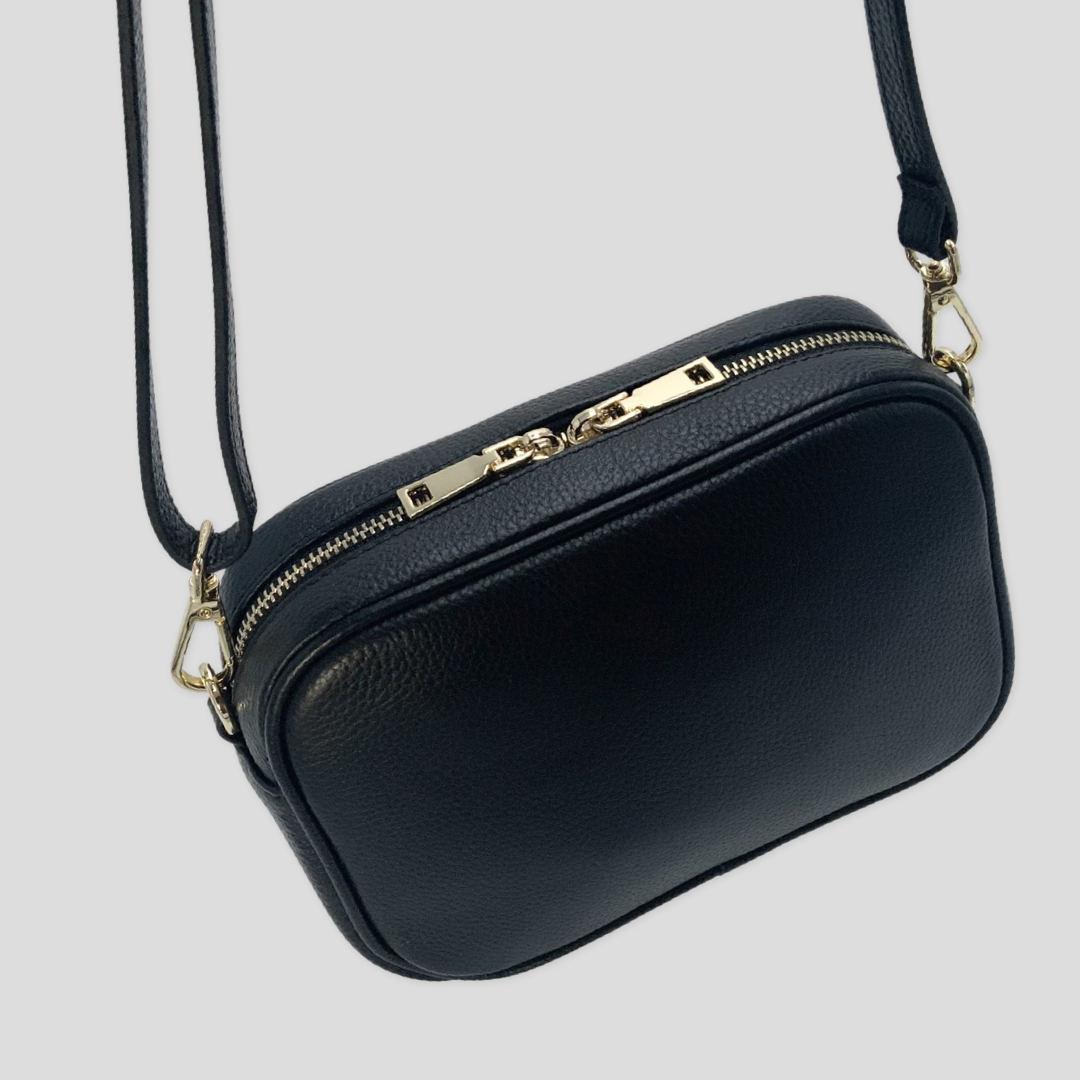 Classic elegance with practicality and versatility in mind. TIKORI classic Black by TIKORI london. Back profile of the bag shows with golden tone hardware in the white background. Bag handing in the strap showing motions.