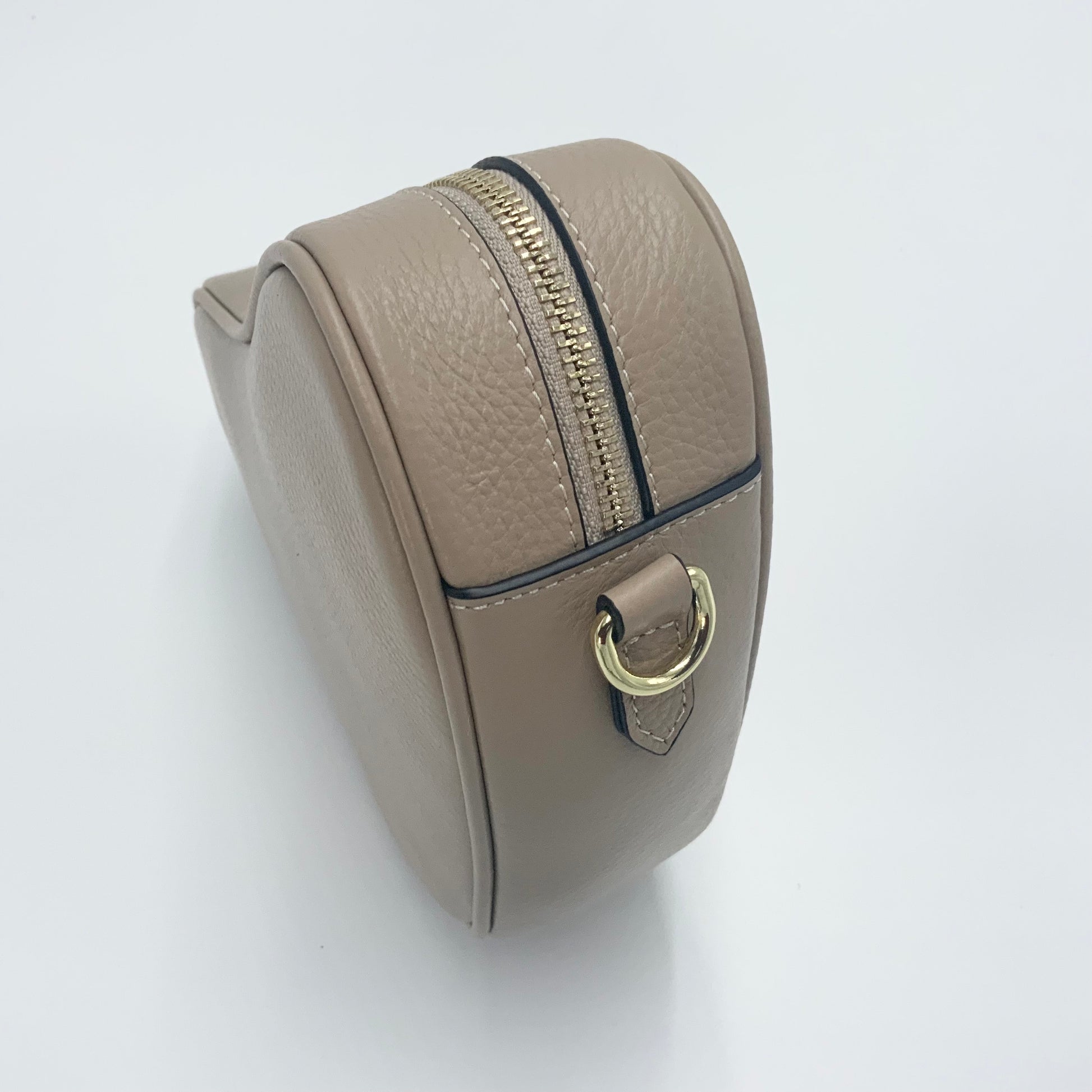 Sand heart-shaped leather crossbody bag by Tikori London, featuring a stylish and compact design perfect for everyday use. Side profile shows in the picture, highlights zipper and side buckle 