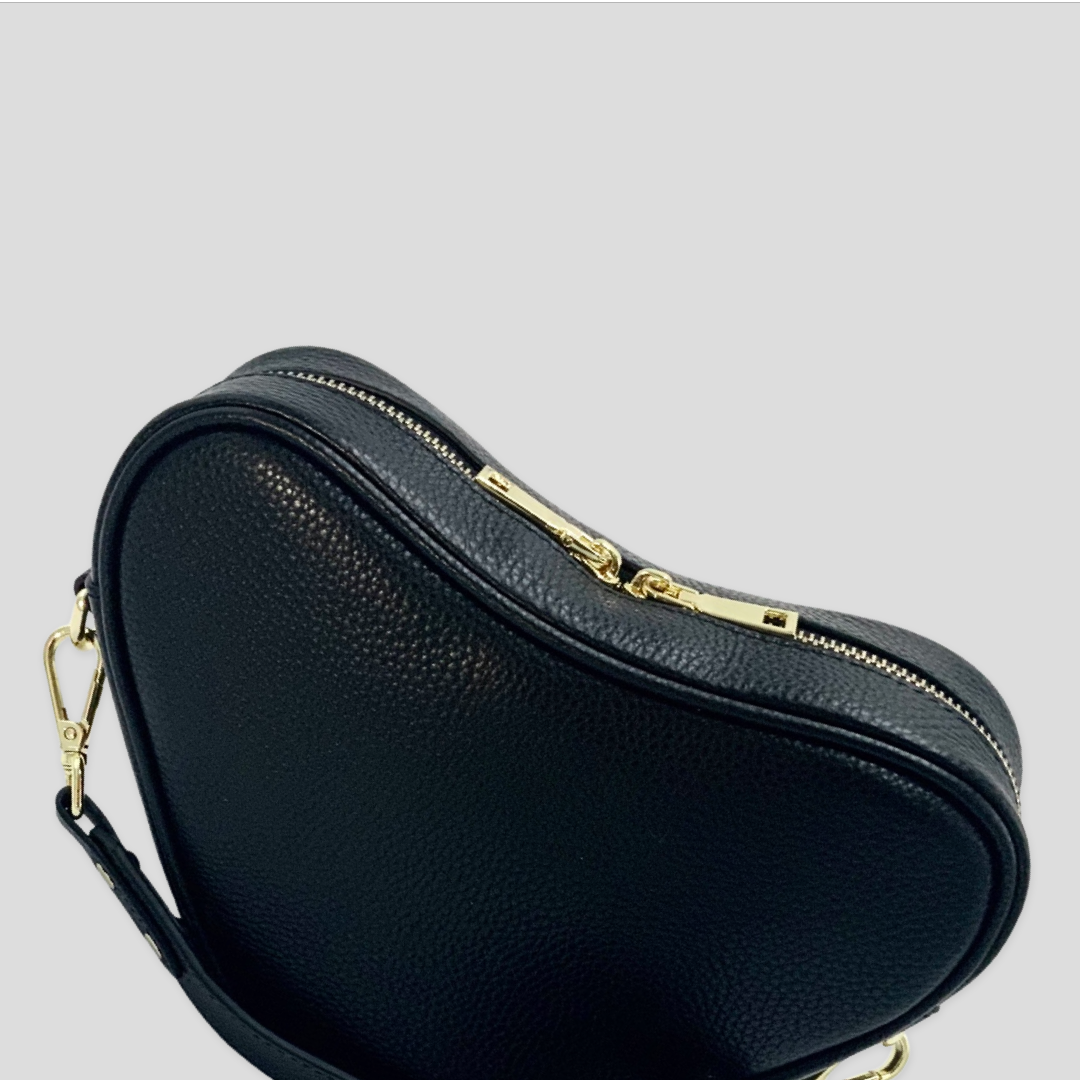 Selene heart crossbody bag by TIKORI London. Genuine premium leather with high quality craftsmanship and exquisite capacity design. Close up detail of the bag showing in the picture. Long adjustable strap and golden tone hardware shows in soft grey colour background.  