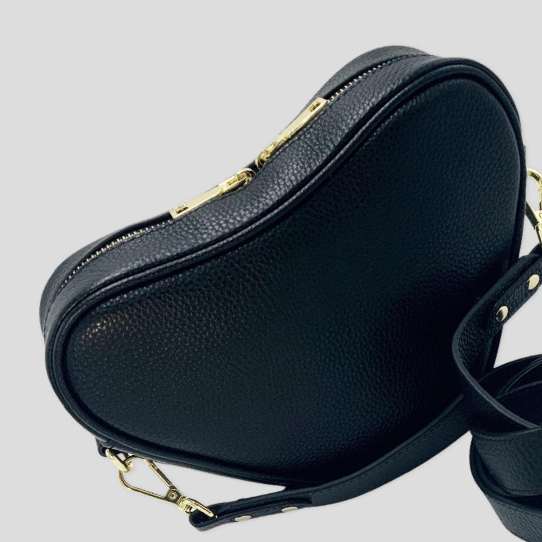 Selene heart crossbody bag by TIKORI London. Genuine premium leather with high quality craftsmanship and exquisite capacity design. Close up details of the bag shows in the picture. adjustable strap and golden tone hardware shows in soft grey natural colour background.