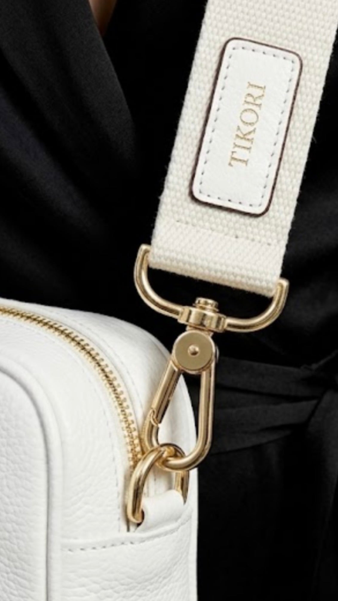 Classic pebbled leather cross body bag - White - TIKORI LONDON. Model in black silk cloths wears the crossbody. Close up detail of the golden tone hardware and canvas strap with TIKORI logo shows in the picture. 
