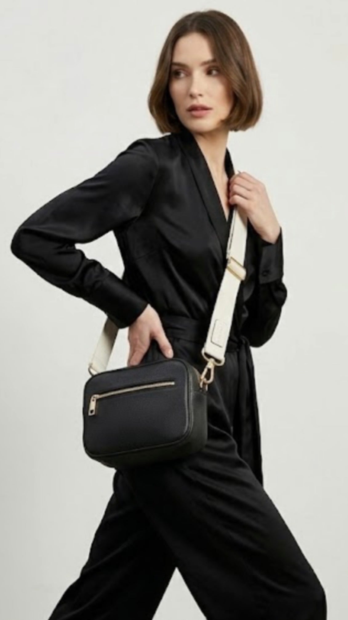 Classic elegance with practicality and versatility in mind. TIKORI classic Black by TIKORI london. Model in black cloths, wears the crossbody. Close up detail the black bag and white canvas strap shows in the picture.