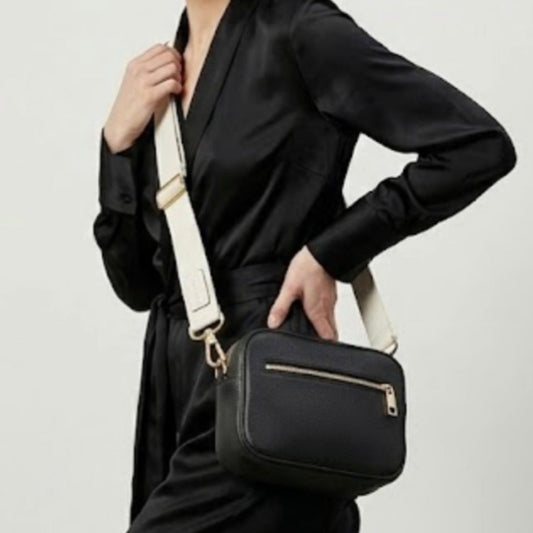Classic elegance with practicality and versatility in mind. TIKORI classic Black by TIKORI london. Model in black cloths, wears the crossbody. Close up detail the black bag and white canvas strap shows in the picture.