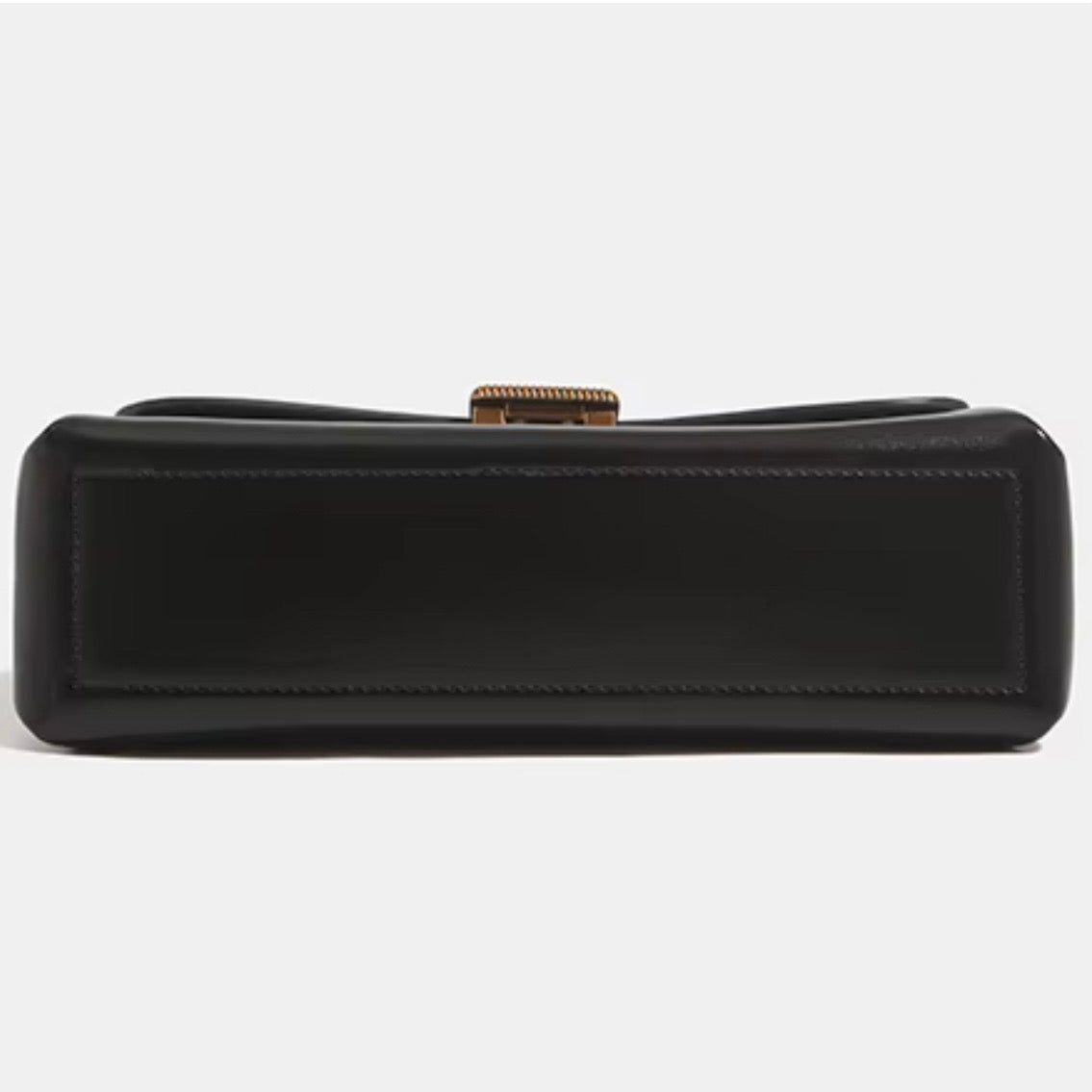 Crimson muse shoulder bag black by TIKOI London. Features a structured, elongated "baguette" body with clean, sharp lines and a narrow profile designed to sit snugly under the arm. Crafted in a vibrant, rich red, smooth polished premium high quality Vegan Leather. Black bags bottom profile showing in the picture in a Fully white background. 