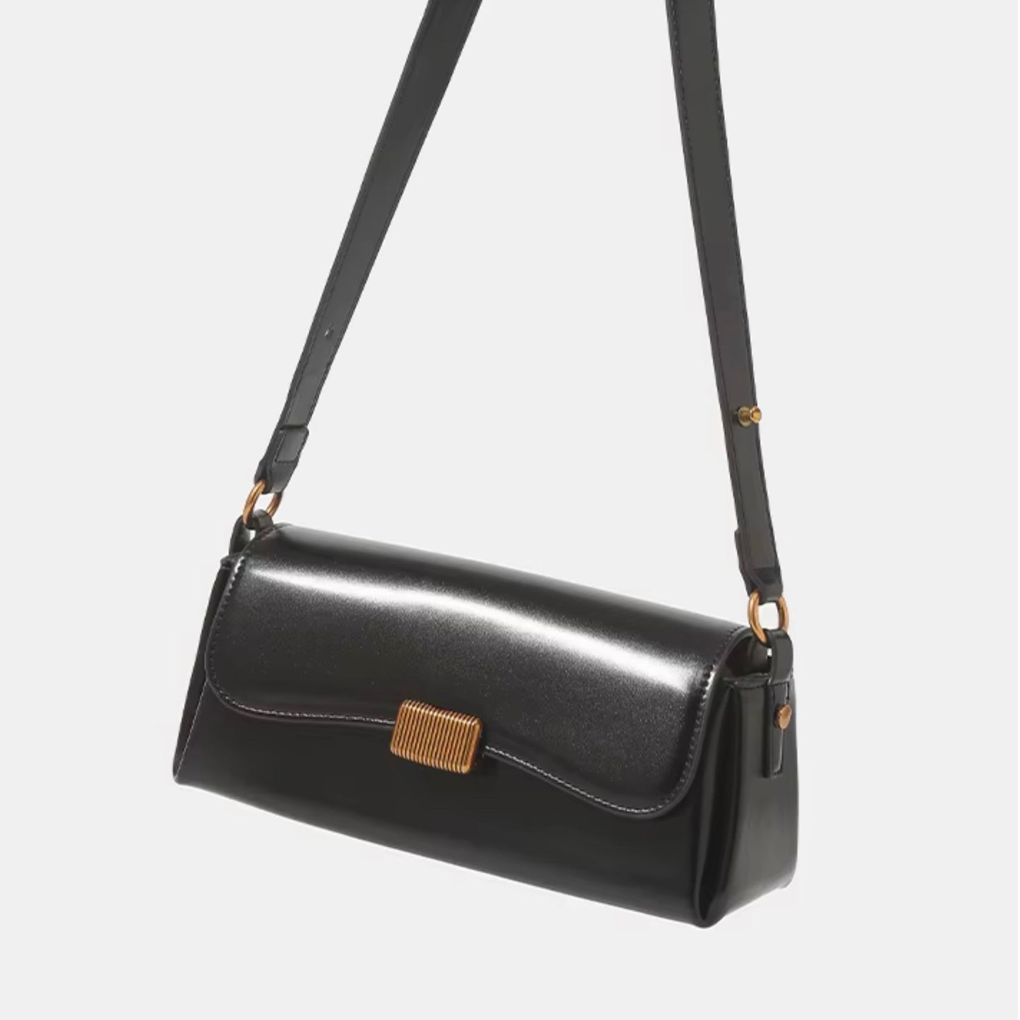 Crimson muse shoulder bag BLACK by TIKORI London. Features a structured, elongated "baguette" body with clean, sharp lines and a narrow profile designed to sit snugly under the arm. Crafted in a vibrant, rich red, smooth polished premium high quality Vegan Leather. Bag showing in a hanging motion in a fully white background shows in the picture.
