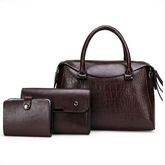 Vintage inspired embossed satchel bag coffee by TIKRI LONDON. This elegant top handle handbag is crafted from rich, deep coffee toned high quality premium Vegan Leather, featuring a sophisticated crocodile embossed panel across the front for a multi textured look. Its structured "doctor bag" silhouette offers a spacious interior, secured by a smooth top zipper. Bag displaying front profile with the matching wallet and card holder in a fully white background.