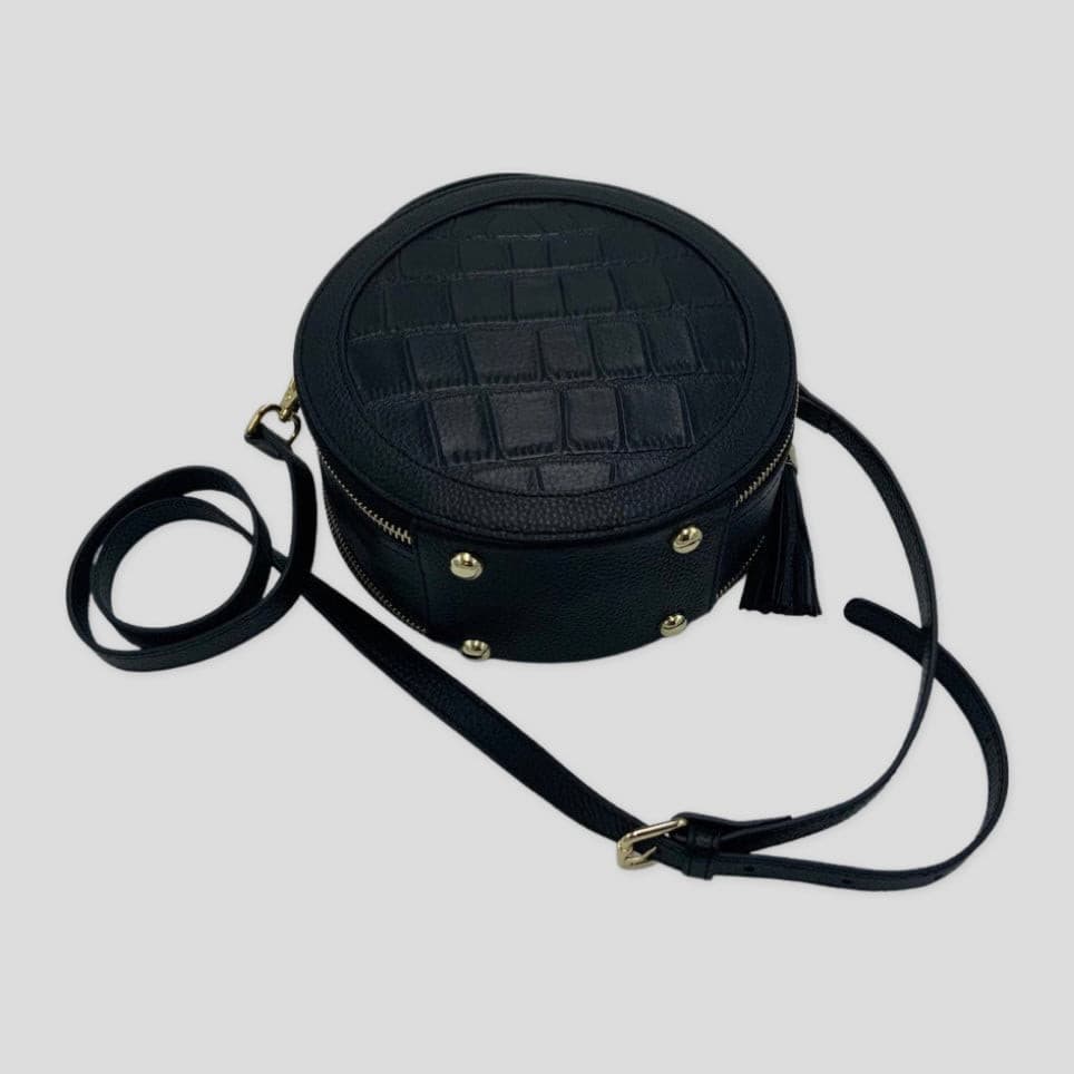 Cleopatra by Tikori London. leather circle crossbody bag with dual zippers. sleek modern design. Bag displaying with the strap. 