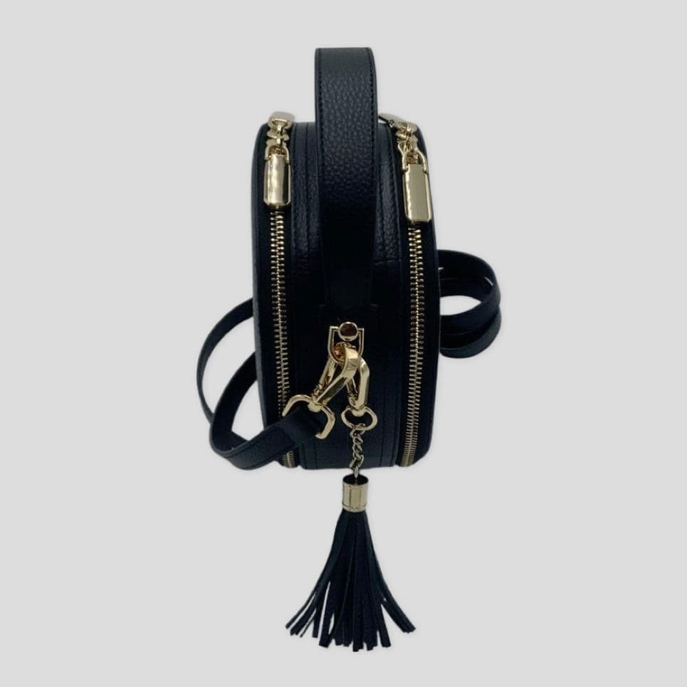 Cleopatra by Tikori London. Black leather circle crossbody bag with dual zip fastening. finished in croc-embossed leather. Side profile of the bag.