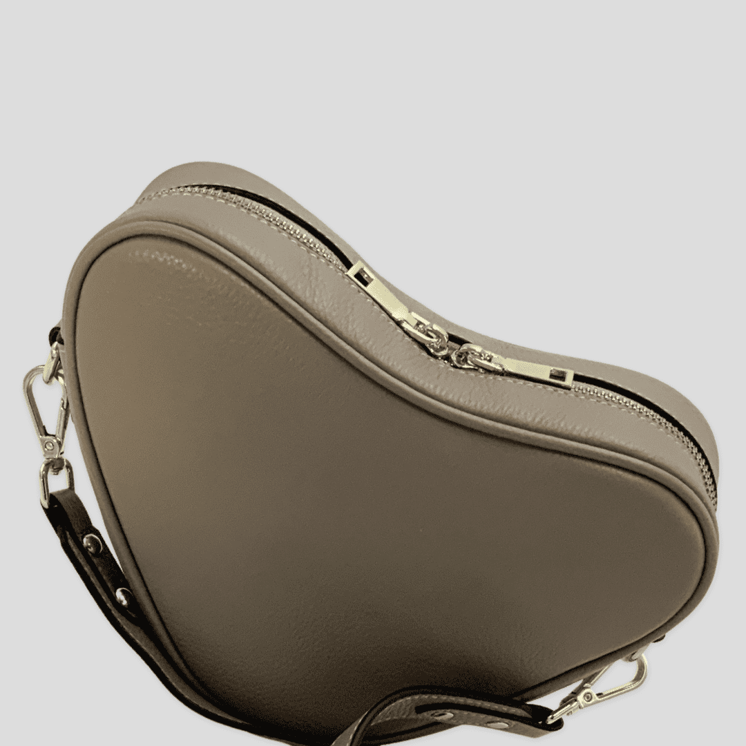 Beige heart-shaped leather crossbody bag by Tikori London with a sleek, modern design and adjustable strap.